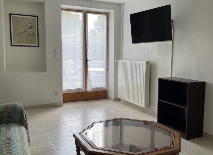 Salon lumineux avec télévision murale et accès direct au jardin